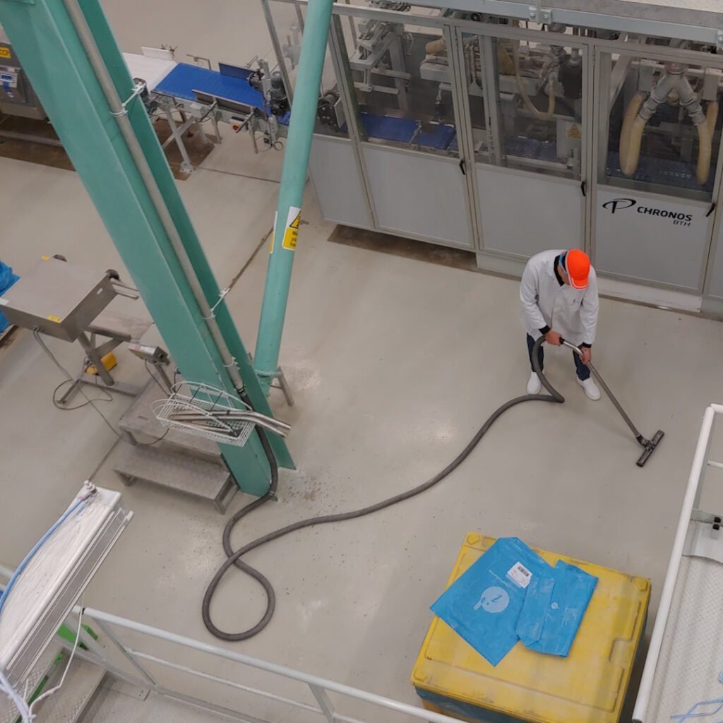 Un hombre utiliza un sistema de aspiración centralizado industrial en una línea de producción alimentaria